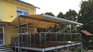 A covered outdoor area with a metal staircase leading up to a platform. - Knüllhotel Tann-Eck (Knullwald)