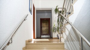 Una escalera con barandas de metal, una puerta de madera y una planta en maceta.