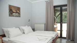 Habitación de hotel con dos camas, un radiador, un cuadro en la pared y vistas a través de la puerta de cristal.