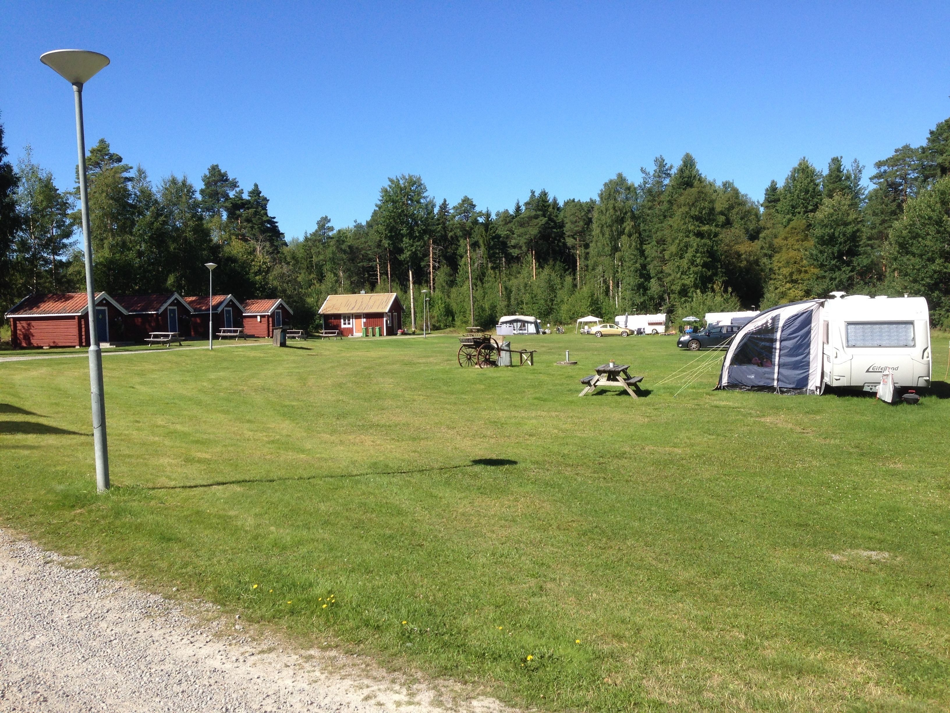 A campground with RVs, picnic tables, and a red building.