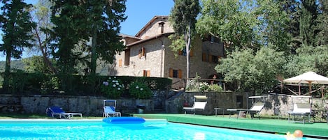 A swimming pool with lounge chairs and a stone building in the background.
