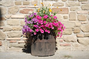 A wooden planter with pink and purple flowers against a stone wall.