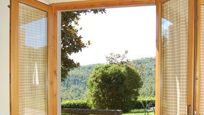 Puerta de madera que da a un jardín con vistas a un árbol y colinas.