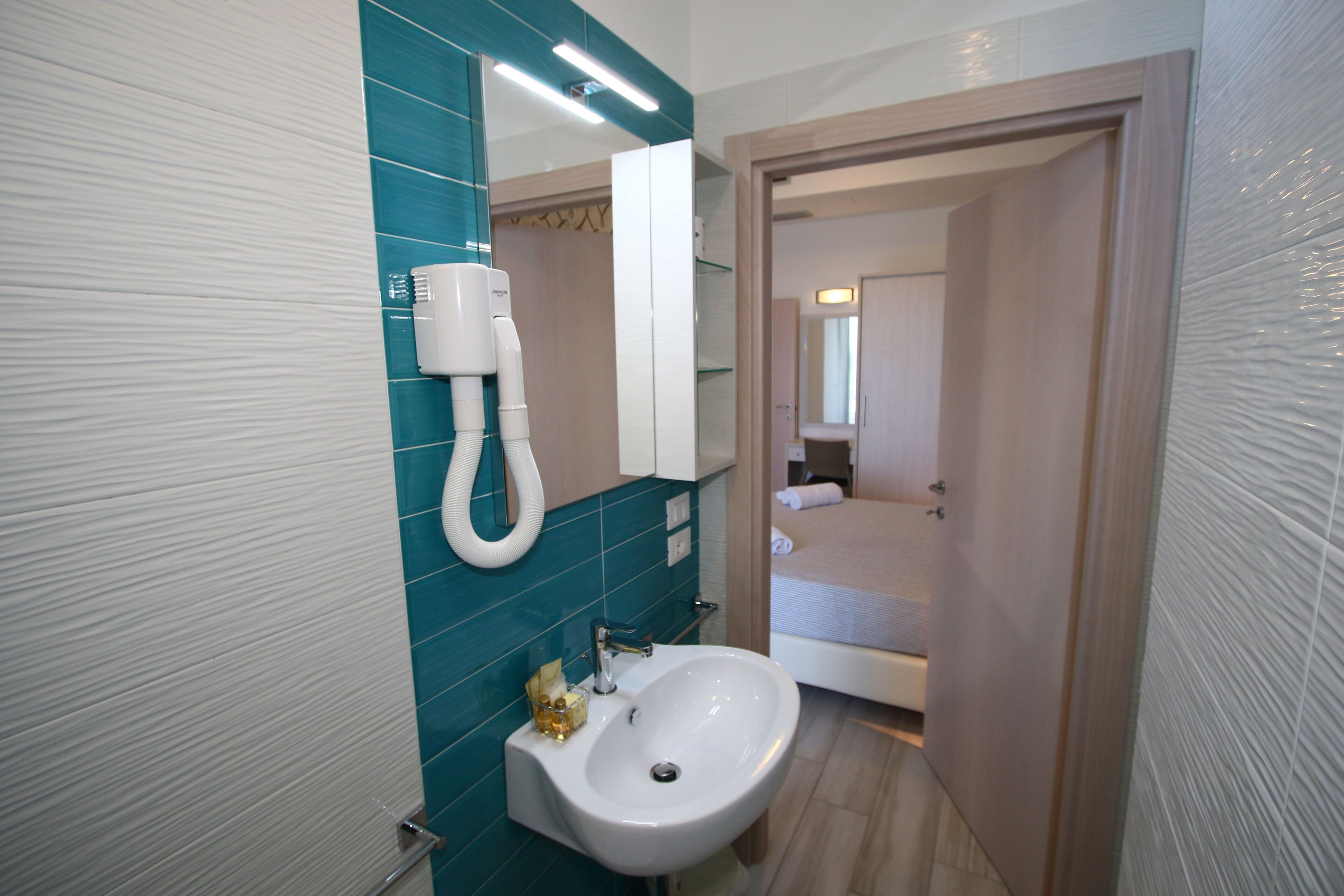 A bathroom with a sink, mirror, and towel rack.