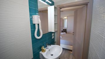 Un baño con lavamanos, espejo y perchero para toallas.