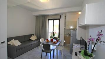 Un espai habitable compacte amb zona de menjador, sofà i petita cuina.