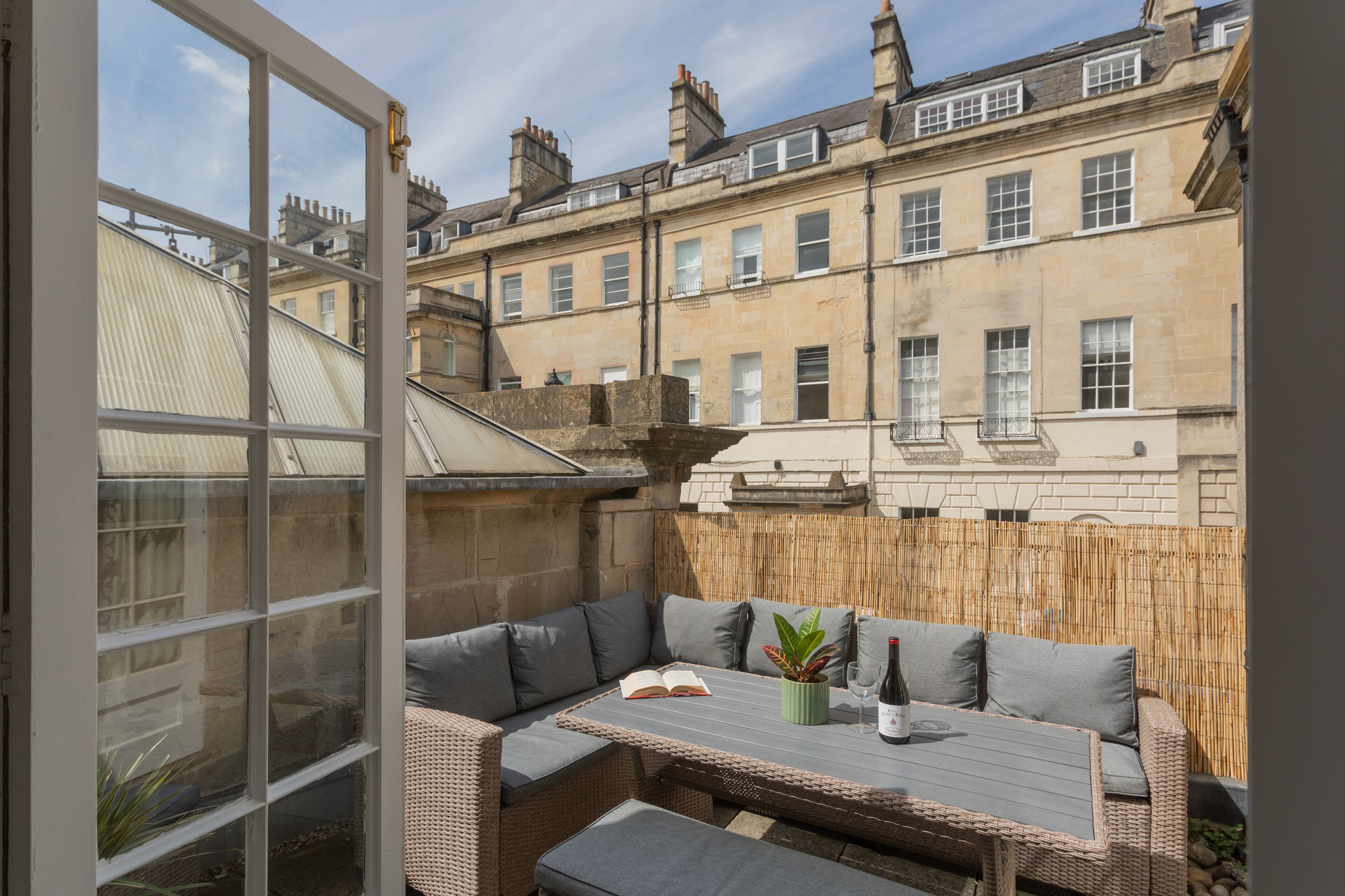 Une terrasse avec des meubles en osier, une table et une plante en pot.