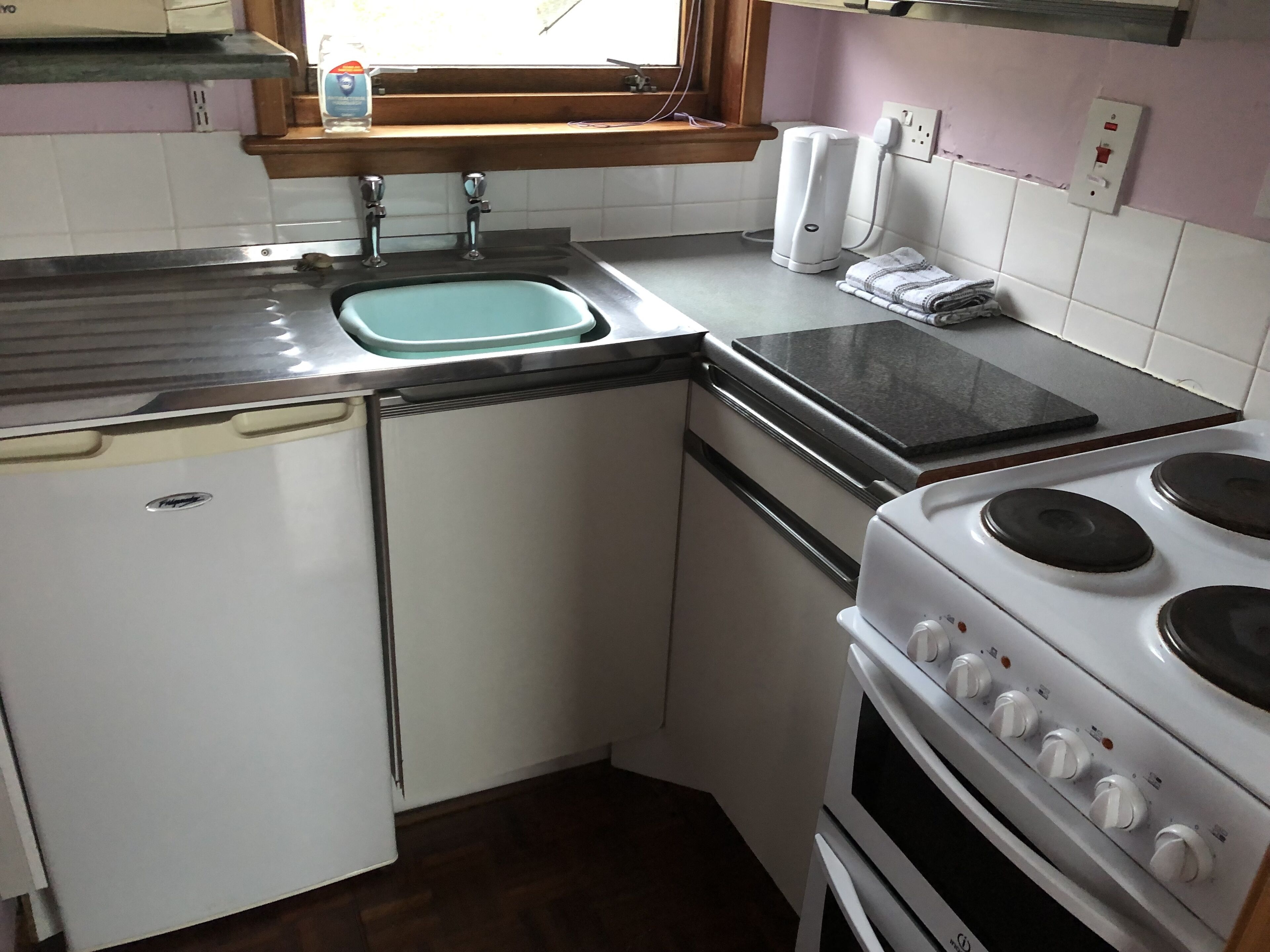 A compact kitchen with a sink, a stove, and a small refrigerator.