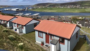 Un pueblo costero con casas adosadas, un puerto deportivo y vistas al mar.