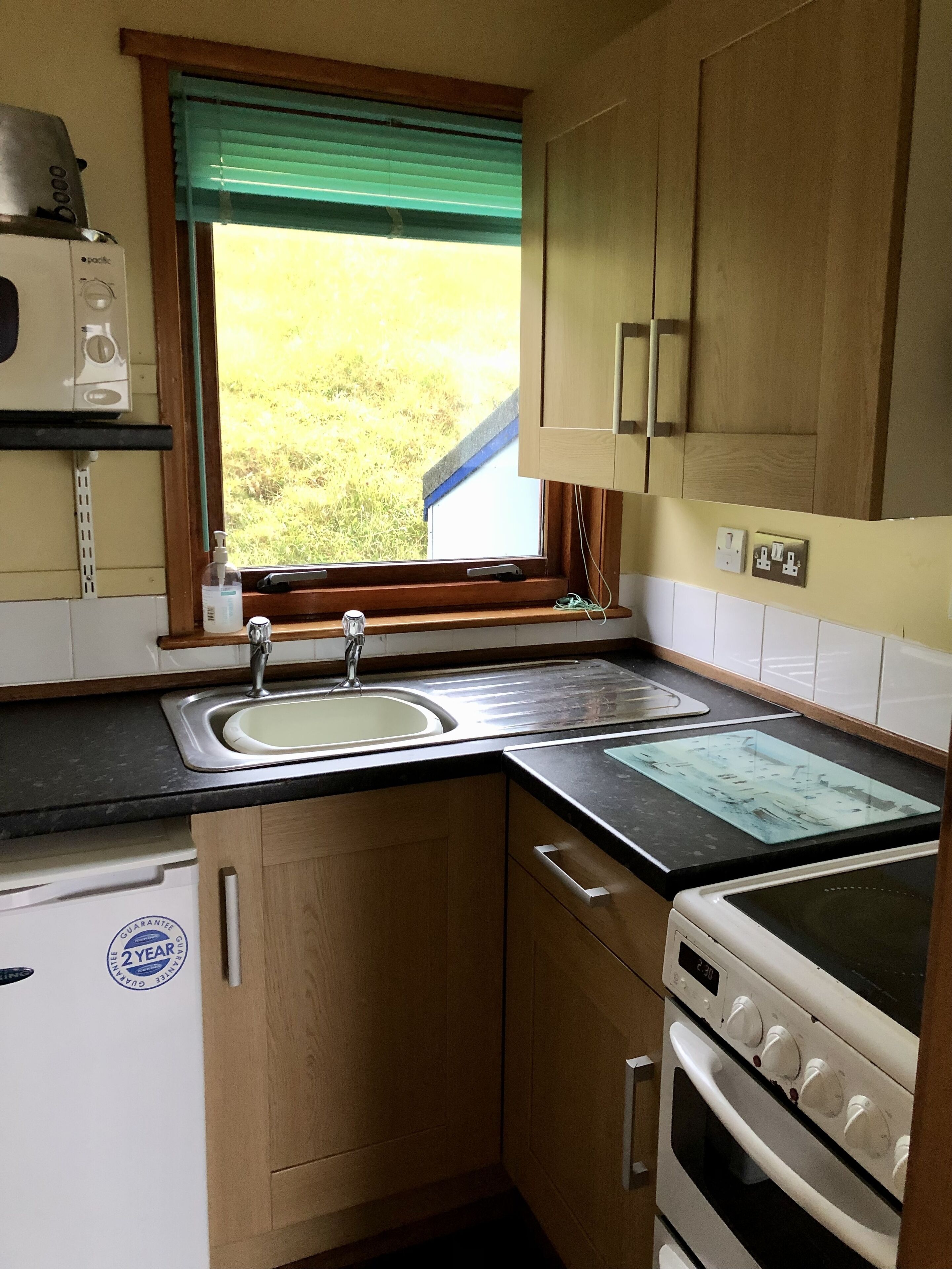 A compact kitchen with a sink, a stove, and wooden cabinets.