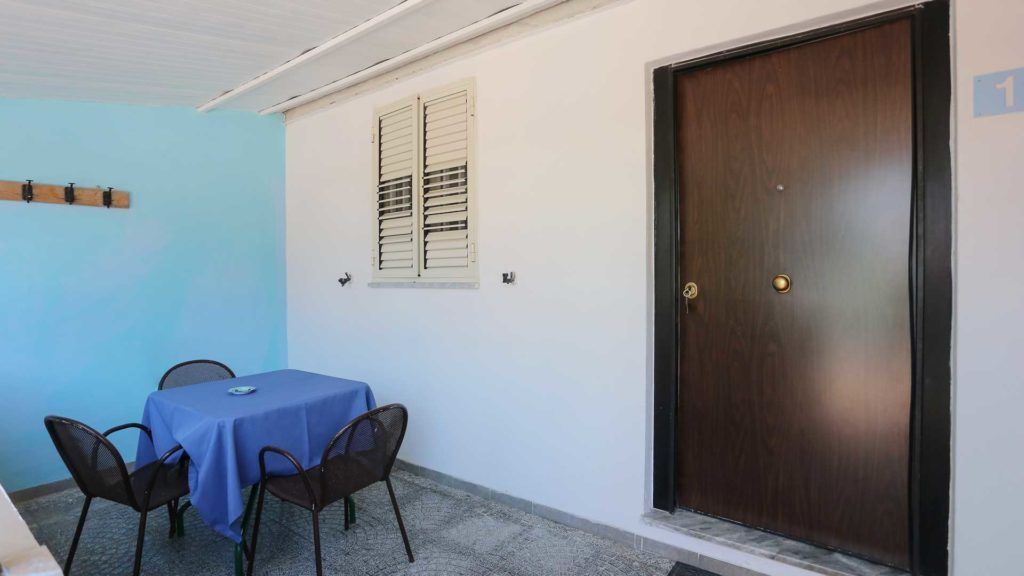 A room with a table and chairs, a door, and a window with shutters.
