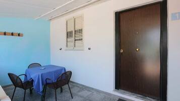 A room with a table and chairs, a door, and a window with shutters.