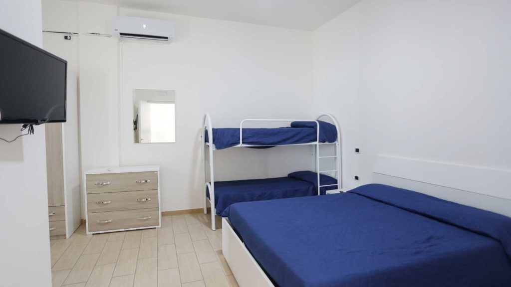 Une chambre avec des lits superposés, une commode, un téléviseur et un miroir.