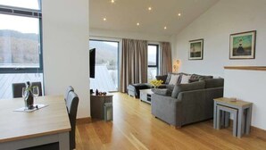 Een moderne woonkamer met een grijze bank, een eettafel met stoelen en een klein bijzettafeltje.