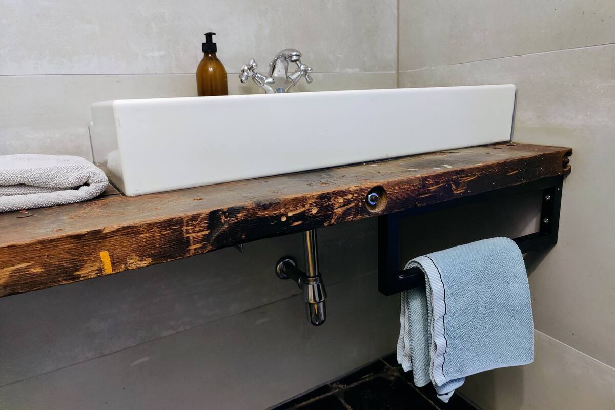 A bathroom with a white sink, wooden countertop, and a towel rack.