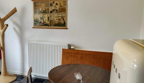 A room with a round wooden table, a wicker chair, a radiator, and a wall-mounted picture. - Wetterdelle (Heers)