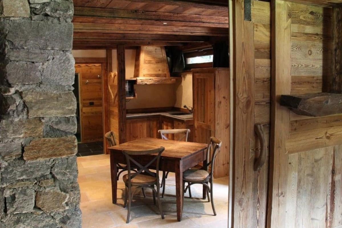 Ein rustikaler Essbereich aus Holz mit einer Steinwand, einem Holztisch und Stühlen.