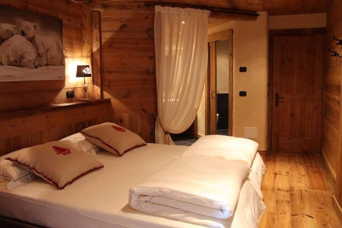 Ein Holzhüttenraum mit einem Bett, einem Polarbärgemälde und einer Tür.