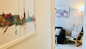 A room with a framed cityscape painting, a black sofa with patterned cushions, a wooden chair, and a map artwork on the wall. - Easter Road Edinburgh Apartment (Edinburgh)