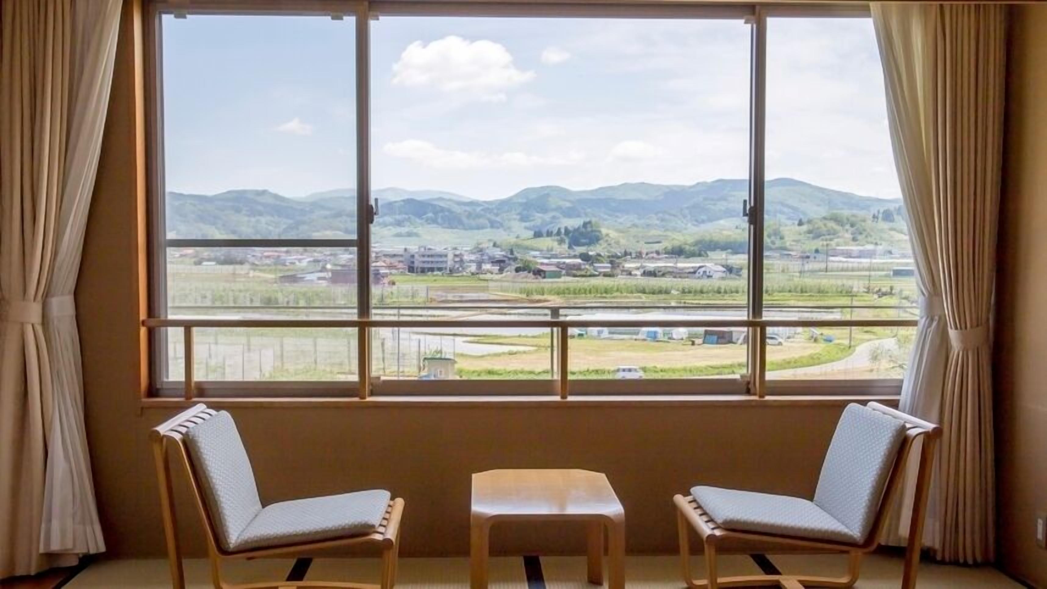 A room with a large window, two chairs, and a small table.
