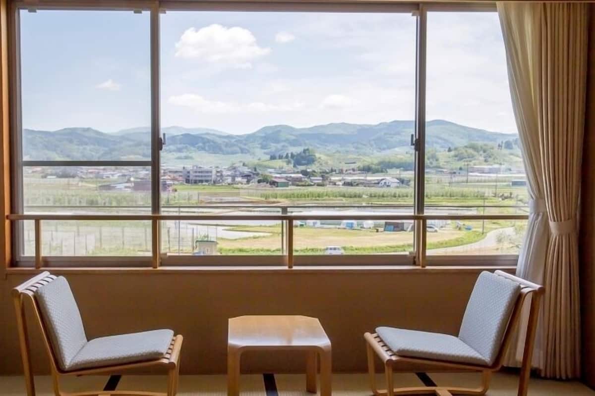 A room with a large window, two chairs, and a small table.