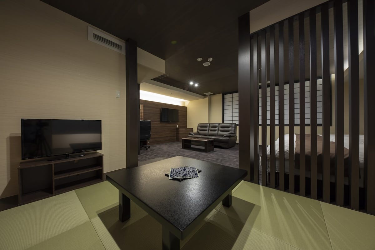 A modern living room with a flat-screen TV, a sofa, a coffee table, and a sliding door.