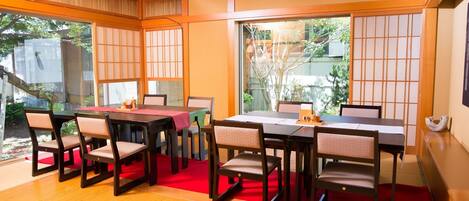 A traditional Japanese-style room with tatami flooring, a low table with a red runner, and shoji screens.