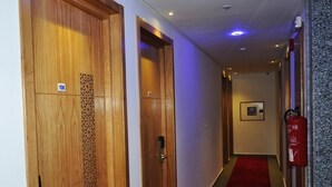 A hallway with wooden doors, a red carpet, and a fire extinguisher. - Dakhla Sur Mer (Dakhla)