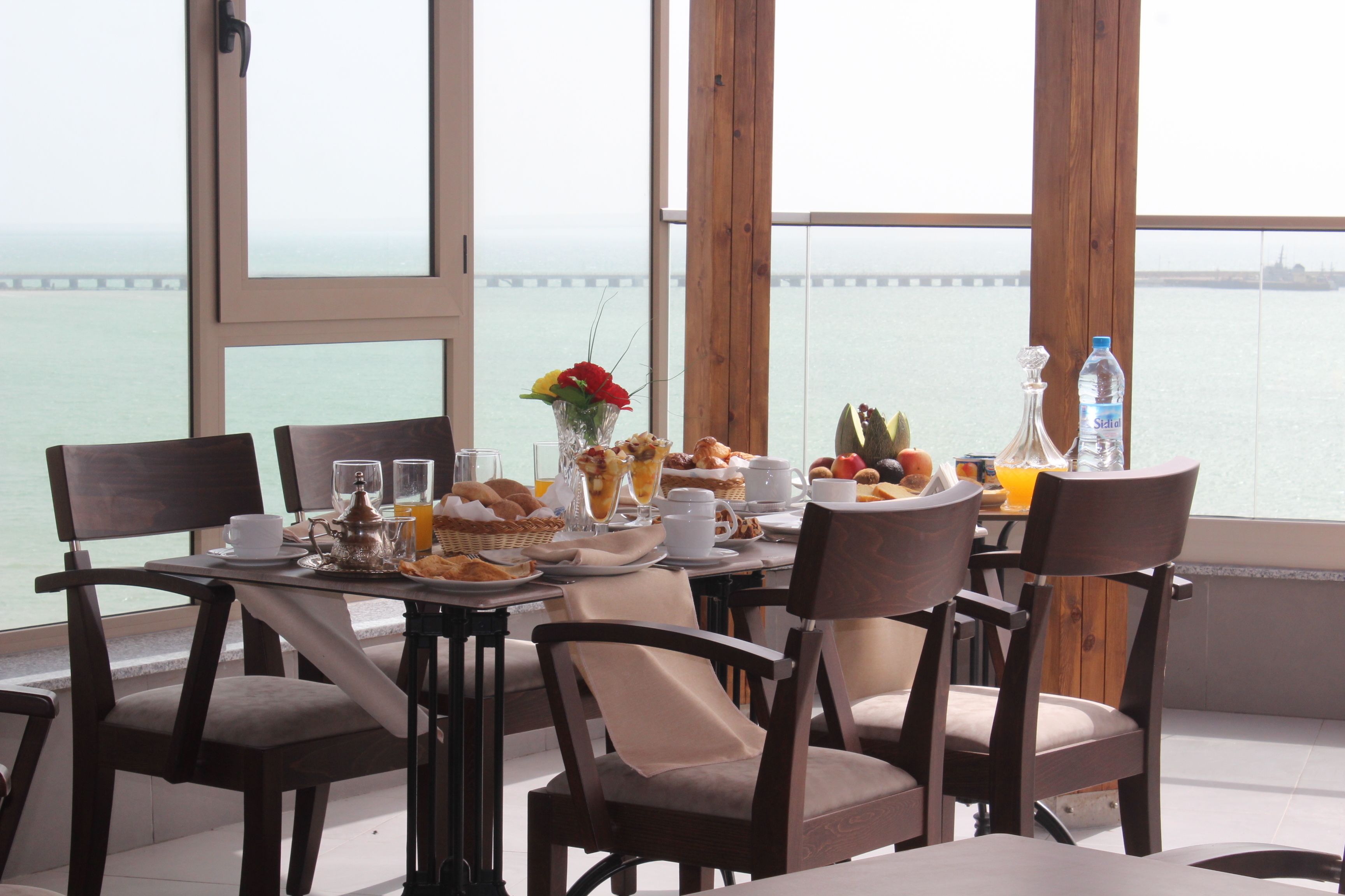 A breakfast table with a view of the sea and a bridge.