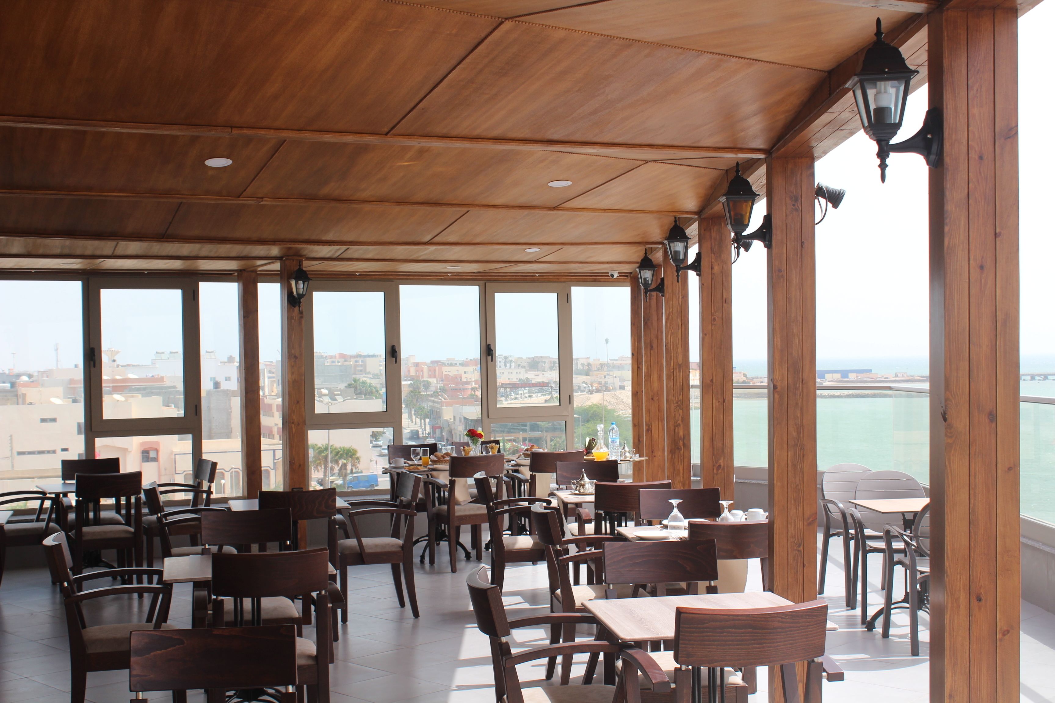 Un restaurant amb mobles de fusta i grans finestres que ofereixen una vista de la ciutat.