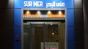 A hotel entrance with a glass door, illuminated signage in multiple languages, and a ramp leading up to the entrance. - Dakhla Sur Mer (Dakhla)