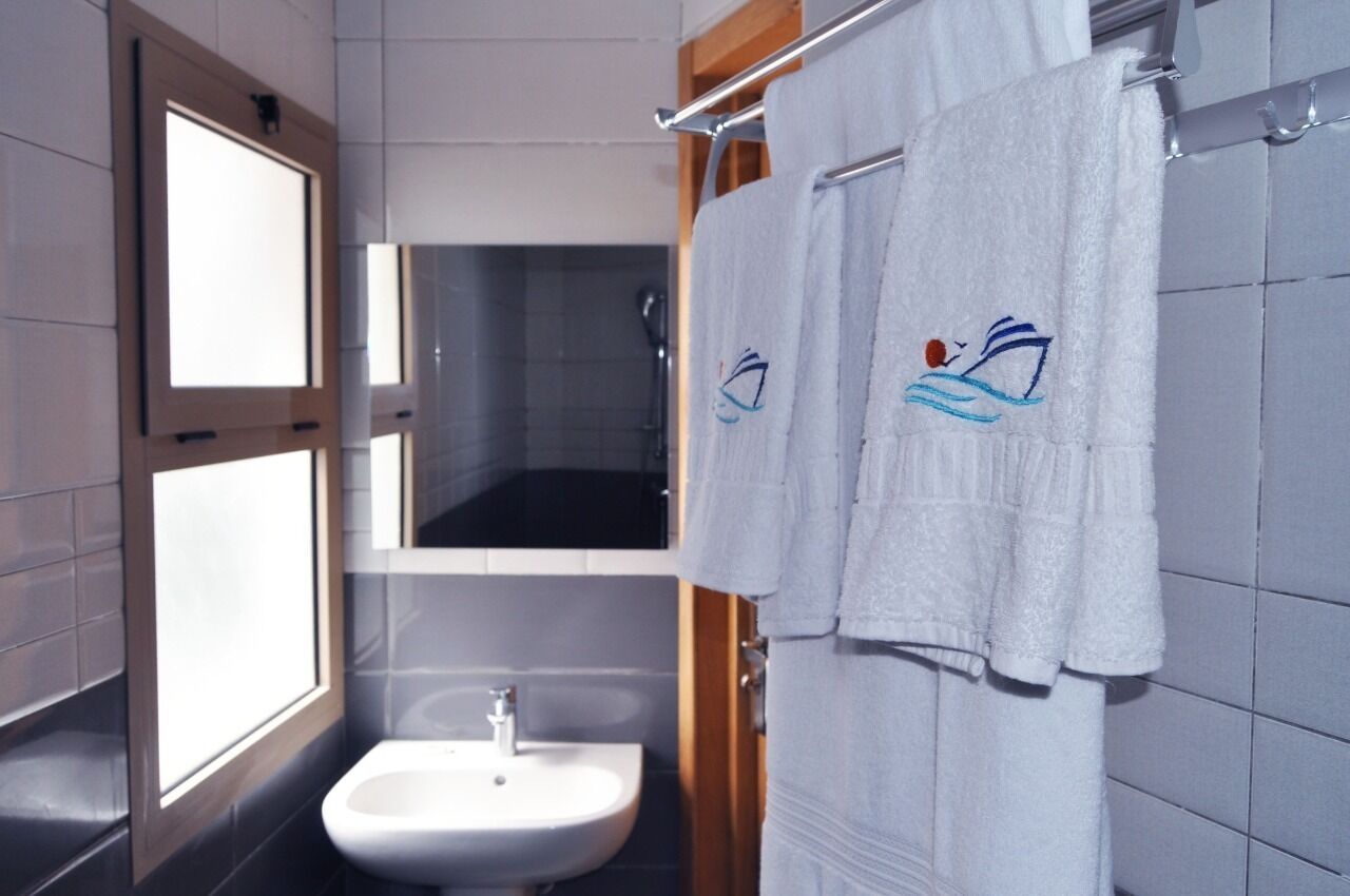 Ein Badezimmer mit Waschbecken, Spiegel und zwei Handtüchern an einem Wäscheständer.