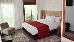 A hotel room with a bed, a chair, a TV, and a view of the outside. - Dakhla Sur Mer (Dakhla)