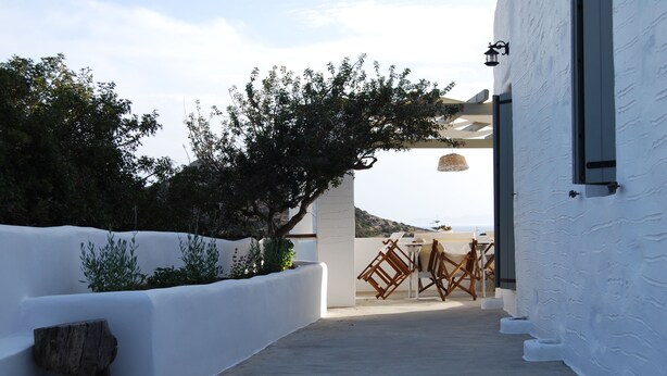 A white-walled building with a wooden bench and a hanging lantern. - Maistrali Studio - House Levante (Syros)