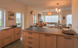A spacious kitchen with a large island, wooden cabinets, and a dining area with a table and chairs. - De Oude Katsei (Gingelom)