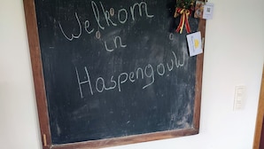 Een schoolbord met de tekst 'Welcome to Haspengouw', een houten bankje en een kleine decoratieve krans.