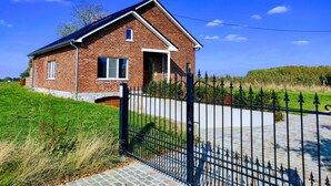 Een tweelaags bakstenen huis met schuin dak, een voordeur en een klein portaaltje.