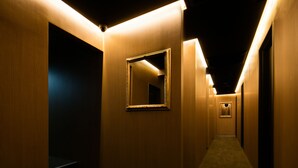 A hallway with wooden walls, a mirror, and a carpeted floor. - Hills Hotel Gotanda (Tokyo)