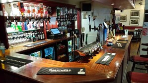 Eine Bar mit einer Theke, mehreren Zapfhähnen und einer Auswahl an Flaschen.