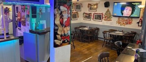 A restaurant with wooden flooring, tables, chairs, and a TV mounted on the wall.