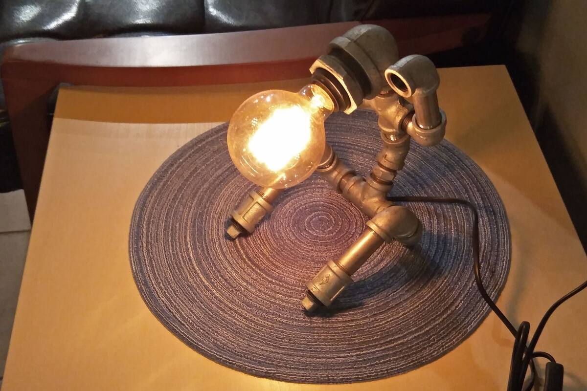A table lamp with a glass shade and brass fittings on a woven placemat.