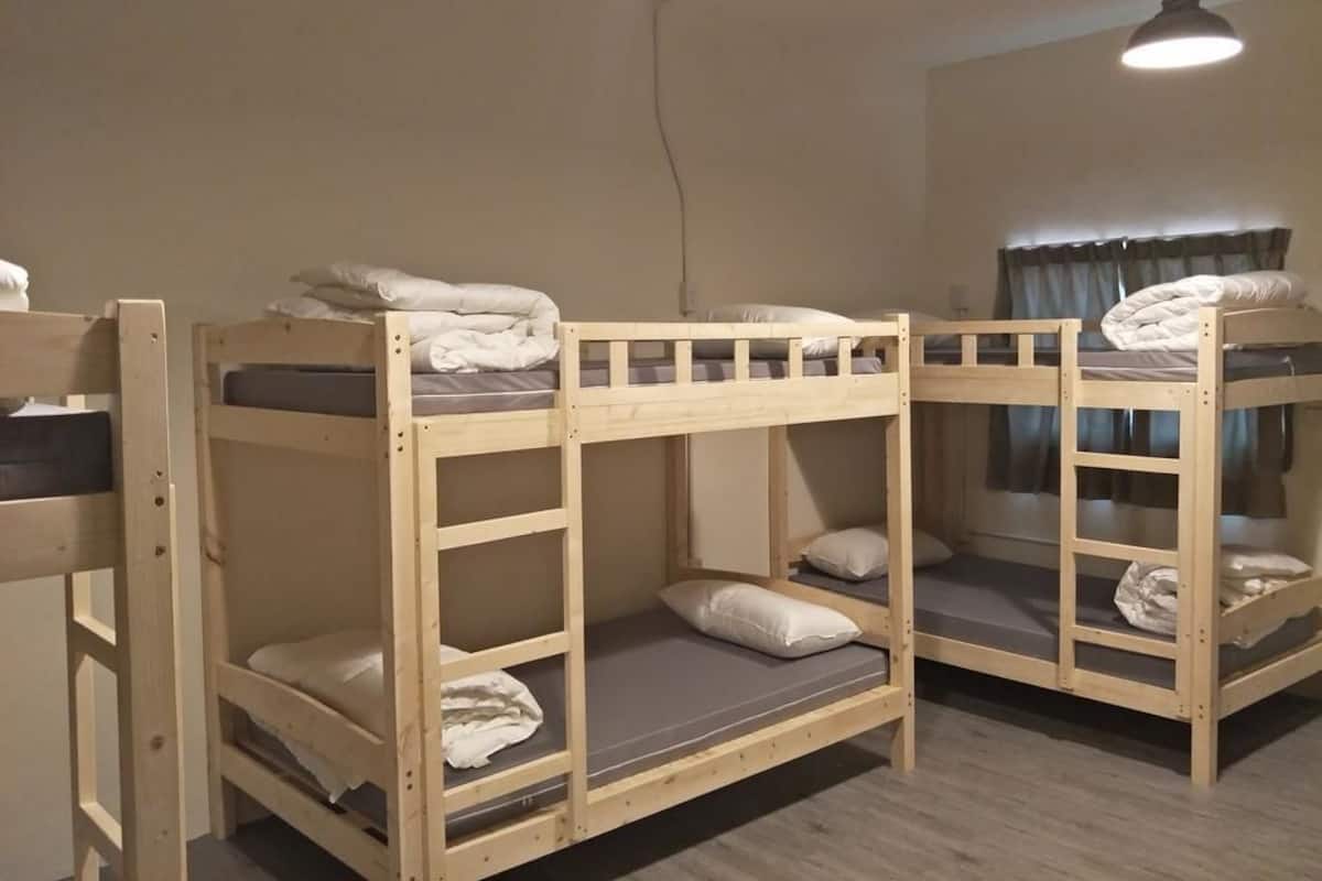 A room with bunk beds, a hanging light fixture, and a window with curtains.