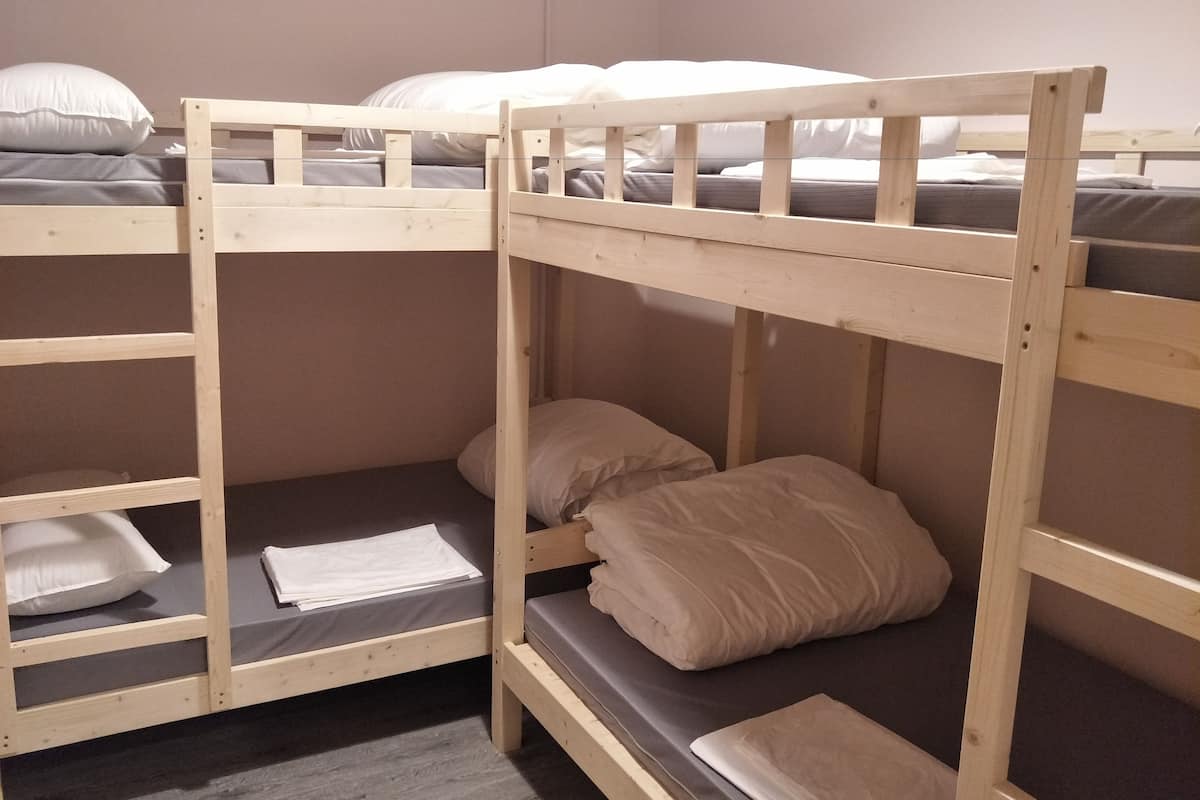 A bunk bed room with two beds, each with pillows and a mattress.