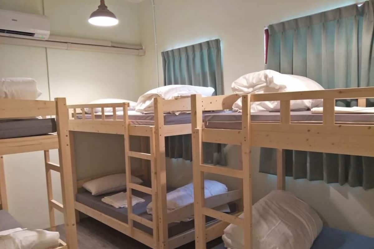 A bunk bed room with a ceiling fan, a window with curtains, and a wall-mounted air conditioner.