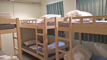 A bunk bed room with a ceiling fan, a window with curtains, and a wall-mounted air conditioner.
