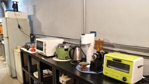 A kitchen with a microwave, a green slow cooker, a coffee maker, and a yellow toaster oven. - B Puli Backpacker Hostel (Puli)