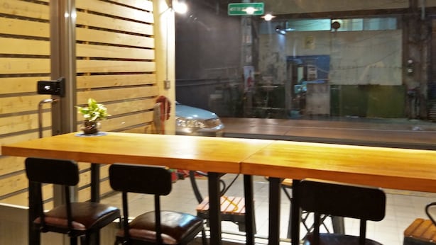 A restaurant with a wooden table and black chairs, a potted plant on the table, and a view of the street outside. - B Puli Backpacker Hostel (Puli)