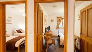A hotel room with a bed, a chair, a desk with a computer, and a window with curtains. - Heads Nook Hall Cottage (Brampton)