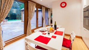 A dining area with a table set for two, a bottle of wine, and a fruit bowl. - Heads Nook Hall Cottage (Brampton)