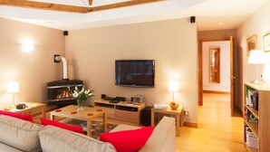 A modern living room with a fireplace, a flat-screen TV, and a cozy seating area. - Heads Nook Hall Cottage (Brampton)